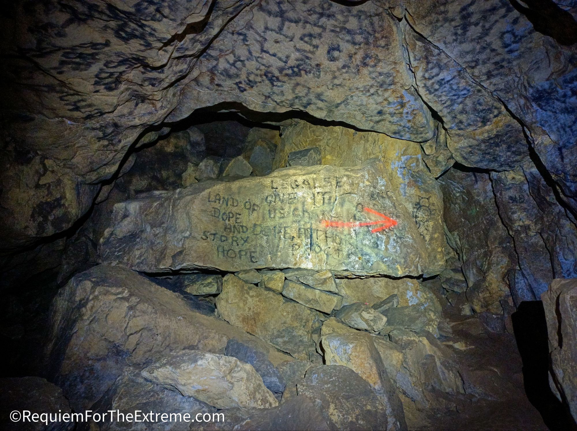 Walls and large boulder covered in the graffiti of the Troggs in Cumberland Cavern Matlock Bath. The Graffiti is written in campfire soot