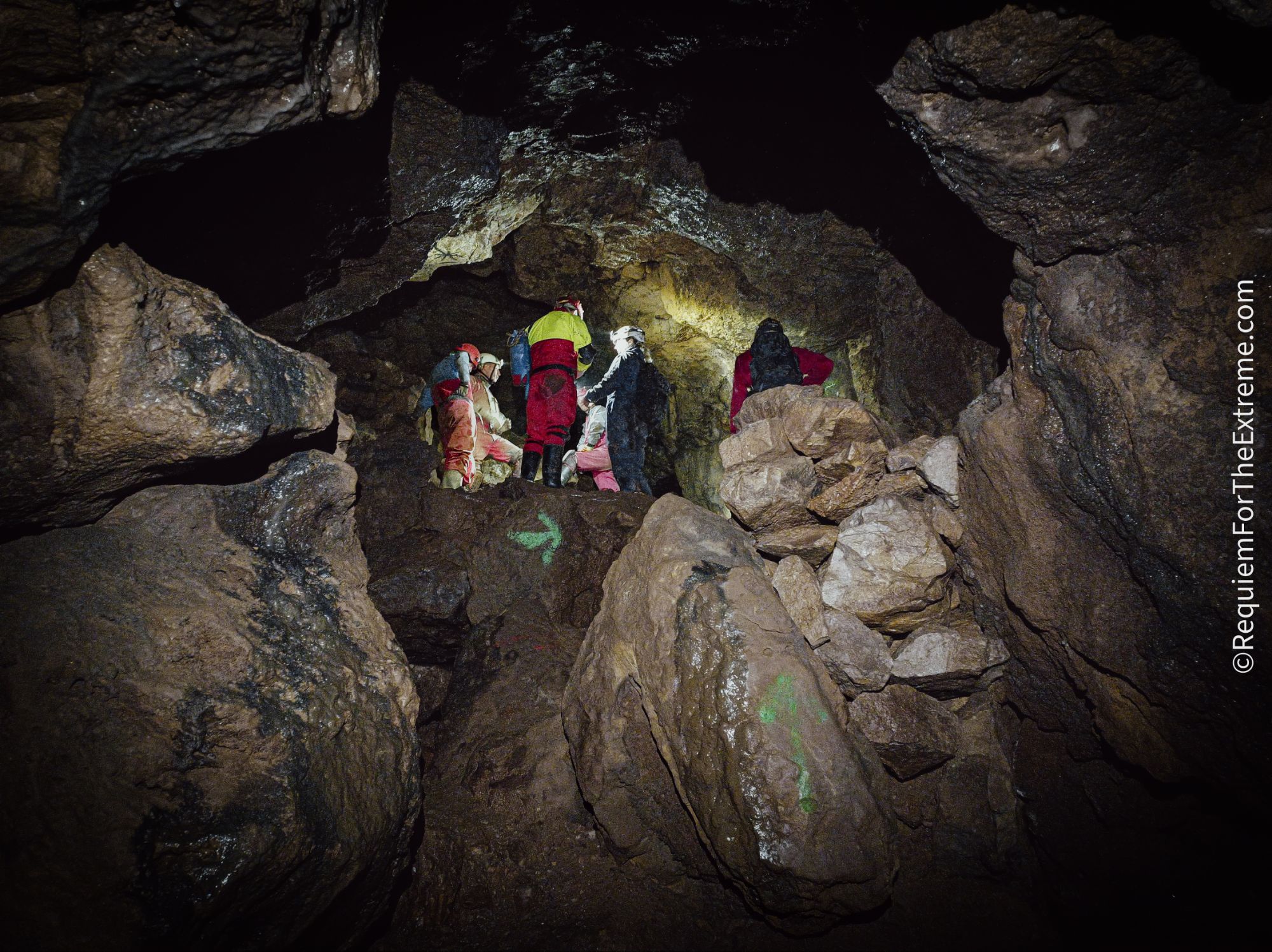 A number of Cavers stand talking in Wapping Mine, Matlock Bath. Large blocks of Limestone lie around them